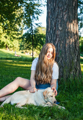 young attractive blond woman playing with her dog in green park at summer, lifestyle people concept
