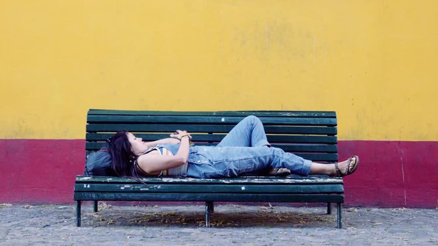 Hispanic woman lay down on the bench relaxing. 4k	