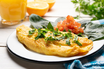 French omelette with tomato and spinach on white background