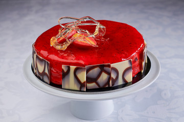 High pastry ice cream cake with decorations and icing for special events on a stand in a photographic set.
