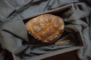 Fresh baked bread in wooden box on gray background