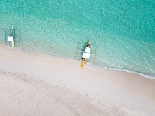 Aerial top down view of white sand beach with a traditional philippine boats beached on it