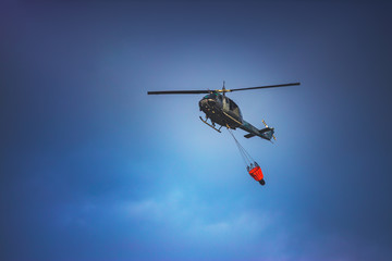 Fototapeta na wymiar Firefighter Helicopter Dropping Sea Water on a Fire over tropical forest