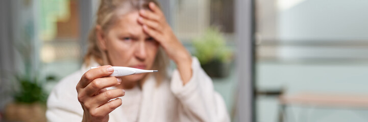 Woman looking at thermometer.Sickness, seasonal virus problem concept. Cold flu and migraine. Focus...