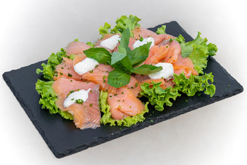 Marinated salmon fillet on a bed of lettuce, mozzarella, basil and olive oil.