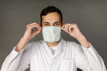 The doctor holds and puts on a medical mask to protect himself from a new virus - the coronavirus