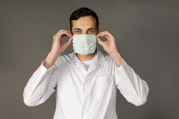 The doctor holds and puts on a medical mask to protect himself from a new virus - the coronavirus