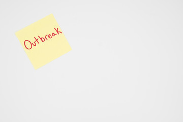 Outbreak in bold red lettering on a yellow sticky note with copyspace