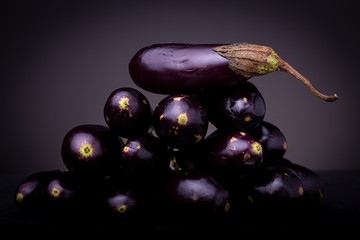 Lot of small colourful vibrant purple baby eggplant aubergine vegetable. Studio still life low key food shot