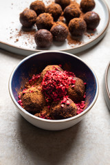 Various Homemade Raw Vegan Truffles or Energy Balls, such as Almond and Cacao, Dark Chocolate and Hazelnut Butter on Grey Plate and Light Background