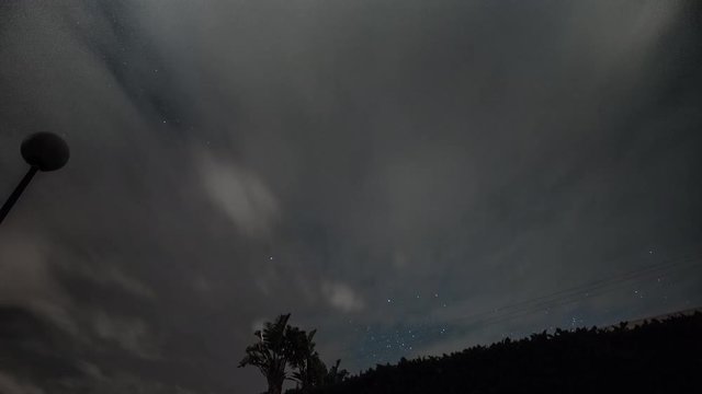 Night timelapse of moving stars and clouds moving in
