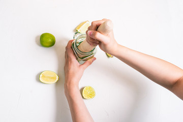 Girl squeezes juice from lime to make mojito. Goth a refreshing summer cocktail.
