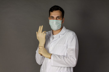 Portrait of a doctor in a medical gown putting on gloves before conducting tests for coronavirus