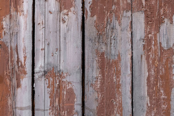 old wooden fence from boards with peeling red paint with cracks. rough surface texture