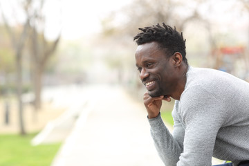 Happy black man looking away sitting at the park