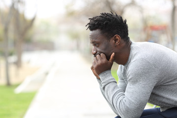Pensive serious black man looking away on a park