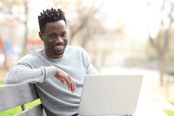 Happy black man with laptop looking at camera