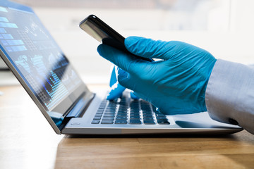 Gloves Protecting From Coronavirus While Using Laptop And Phone