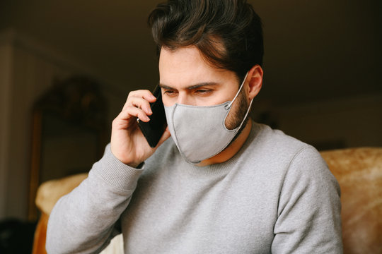 Close-up portrait of young bearded man get a virus and using a medical mask. Quarantine at home.