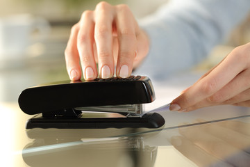 Girl hands using stapler on documents over a desk at home