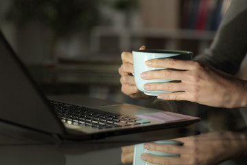 Girl hands watching media on laptop at night with coffee