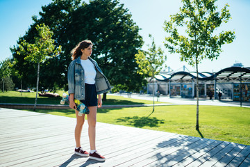 Active woman with skateboard walking in city park