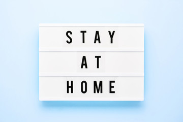STAY AT HOME written in light box on blue background. Healthcare and medical concept. Top view. Quarantine concept.