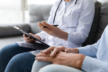 Close up of female doctor visit sick senior woman at home write medicine prescription for pensioner, attentive nurse talk consult ill mature grandmother give help and care, elderly healthcare concept