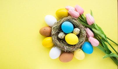colored Easter eggs in nest top yellow view background, selective focus image. Happy Easter card