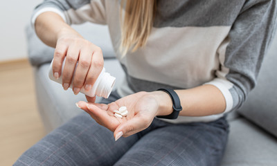Hands holding a jar with pills. Woman using pills