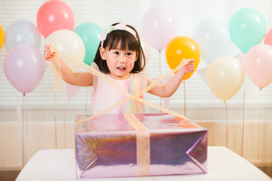 toddler girl unpacking birthday gift box on her birthday party