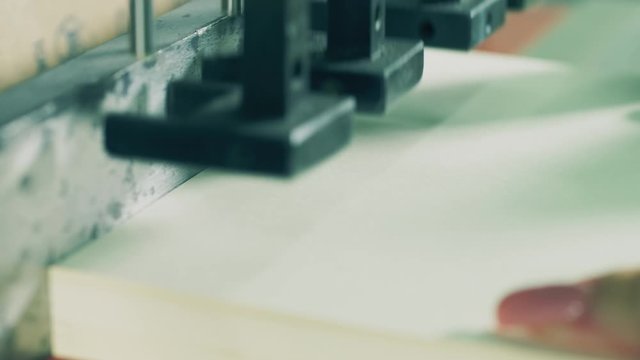 Close up of holes getting punched in a ream of paper