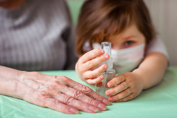 hands of a little girl, and her grandmother's hands with a bottle of dysenfector