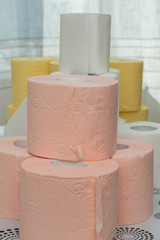 Rolls of white, yellow, red and green toilet paper on the background of hanging gray toilet paper tapes. Coronovirus Currency