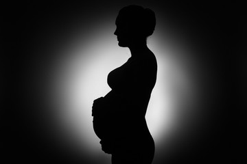 silhouette of  pregnant woman. black and white studio portrait of pregnant  woman close up. 9 months of healthy pregnancy and motherhood. woman waiting for baby. woman in anticipation of child birth. 