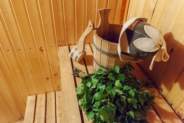 Fototapeta na wymiar Interior details Finnish sauna steam room bathhouse with traditional sauna accessories basin birch broom scoop felt hat