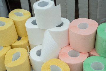 Rolls of white, yellow, red and green toilet paper on the background of hanging gray toilet paper tapes. Coronovirus Currency