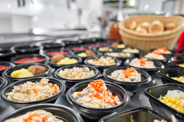 Row of plastic disposable lunch box with healthy natural food. Soups, cream soup, main course with side dish, salads. Food delivery. Lunch in the office.