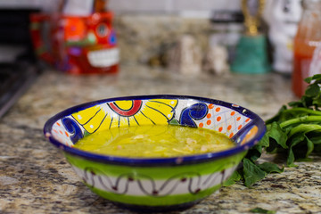 Delicious mexican dish called pozole in a colorful plate on a table.
