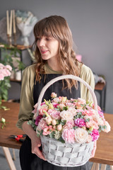 Fototapeta premium Small flower shop and Flowers delivery. Flower arrangement in Wicker basket. Beautiful bouquet of mixed flowers in woman hand. Handsome fresh bouquet.