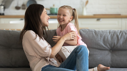 Overjoyed young mother and little preschooler daughter have fun at home involved in funny childish...