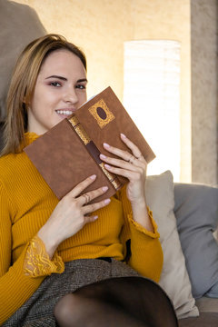 happy young girl with a book in her hands looks at the camera with a smile