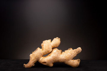 Still life low key studio image of fresh ginger root against a dark background with spotlight on the spice