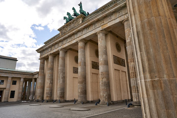 Obraz premium View on the famous Brandenburg gate on the Pariser square during the dusk in Berlin city, parisian square without tourists and visitors - deserted, sunset with blue sky and small clouds