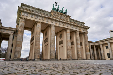 Obraz premium View on the famous Brandenburg gate on the Pariser square during the dusk in Berlin city, parisian square without tourists and visitors - deserted, sunset with blue sky and small clouds
