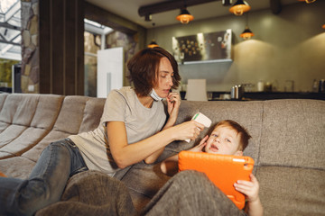 Obraz premium Family stay at home. Mother with little son. Coronavirus theme. Mom measures baby's temperature.