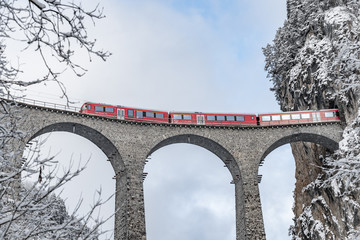 Het Landwasser-viaduct met beroemde trein van rode kleur in de winter, oriëntatiepunt van Zwitserland, sneeuwt, Glacier express