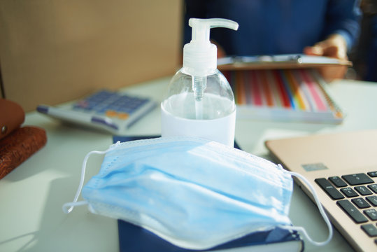 medical mask and hand disinfectant on table in home office