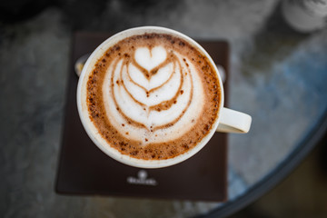 A bird's eye view of white coffee with cocoa , white coffee with black background, coffee served in cafe, morning cappuccino, macchiato in a professional way