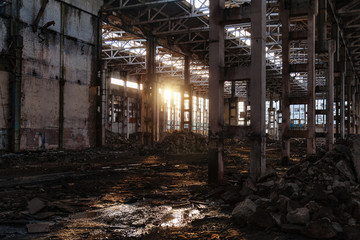 Fototapeta na wymiar Sunlight of sunset in large abandoned industrial building of Voronezh excavator factory
